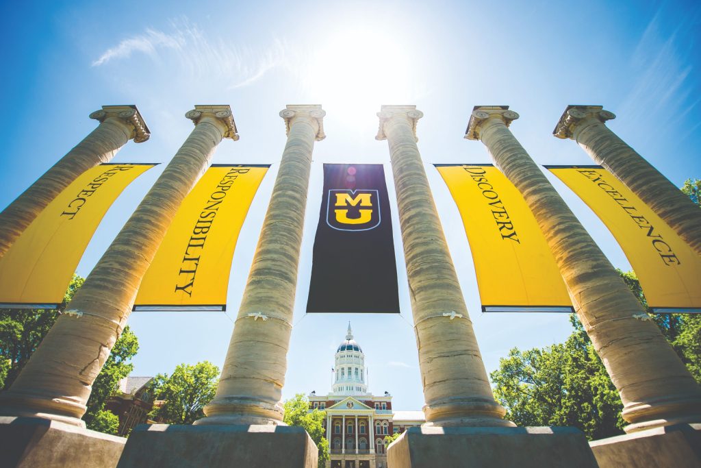MU campus building with pillars and hanging yellow and black banners with respect, responsibility, MU, discovery, and excellence.