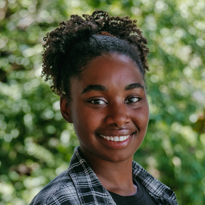 A woman with her hair pulled up wearing a black plaid shirt.
