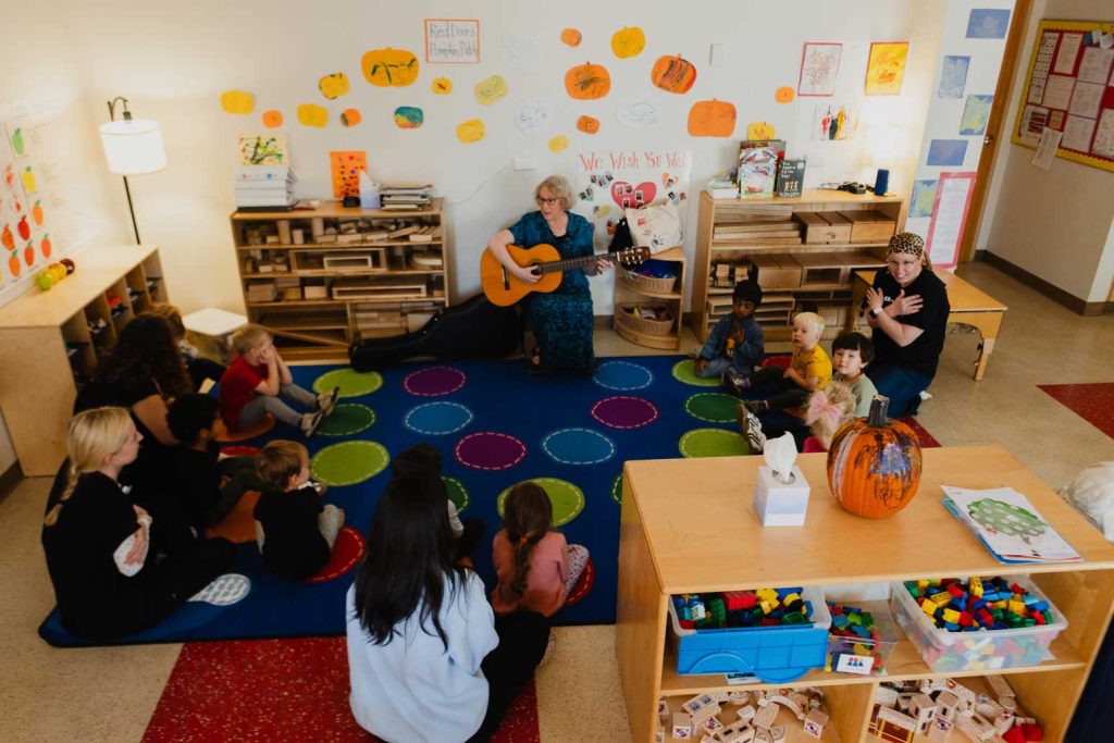 a music teacher plays a guitar to preschool aged children in a classroom at the Child Development Lab.