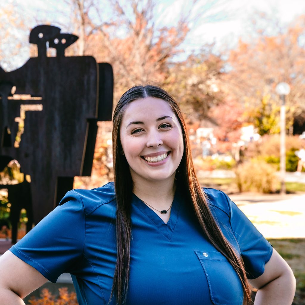 A woman with long brown hair wearing a blue shirt.