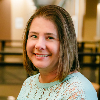 A woman with brownish short hair wearing a light blue sweater.