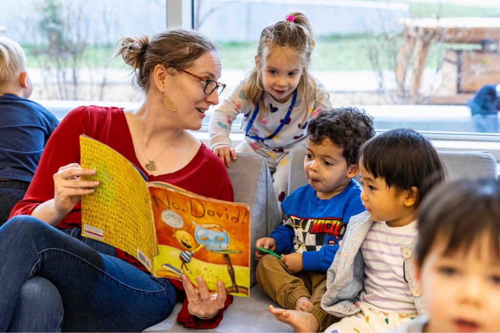 A woman reads a book to young children at the Child Development Lab.