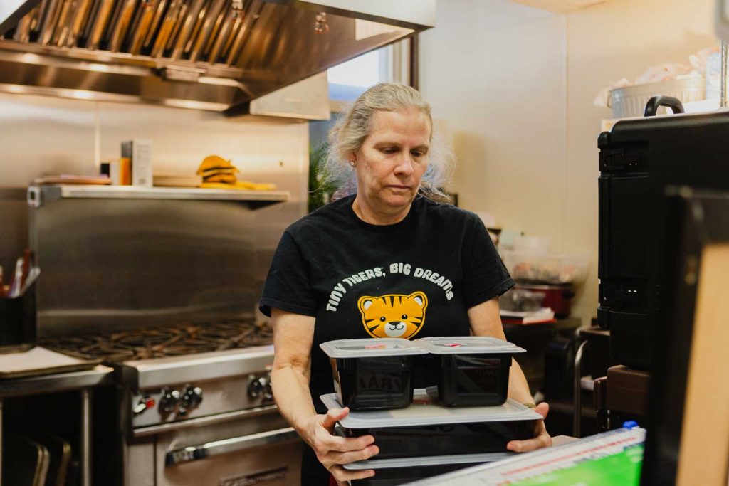 A chef stands in a kitchen and carries prepared meals for children at the Child Development Lab.