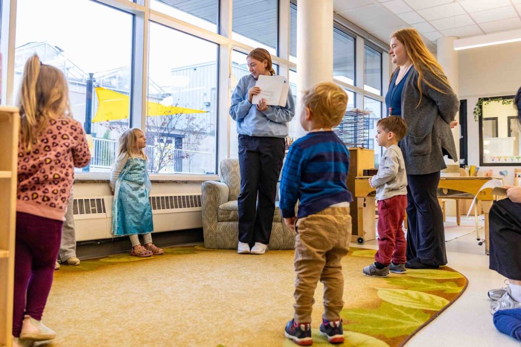 Two early childhood teachers read to children in green door at the Child Development Lab.
