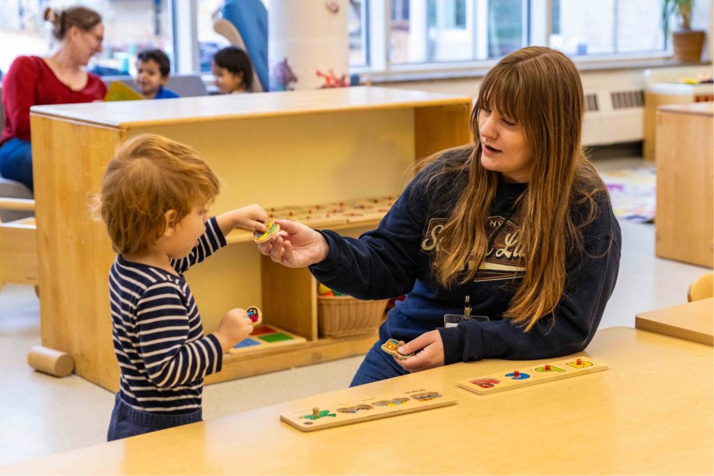 An early childhood professional works with a child at a table.
