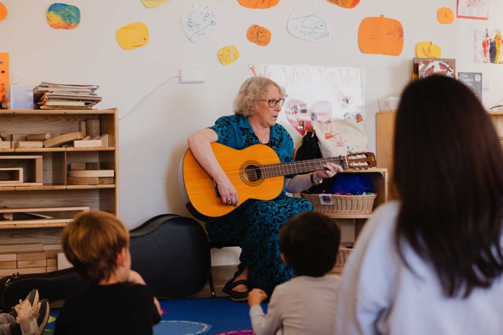 A music teacher plays a guitar for preschool age children at the Child Development Lab.